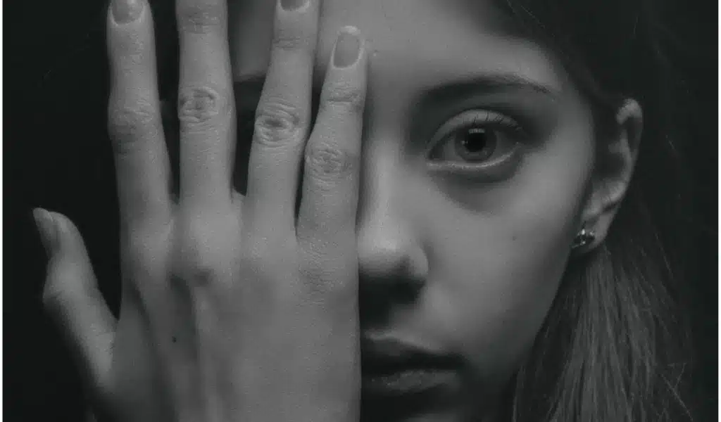 Photos en noir et blanc du visage d'une femme qui ne montre que l'a moitié de son visage. Elle semble sans émotions.