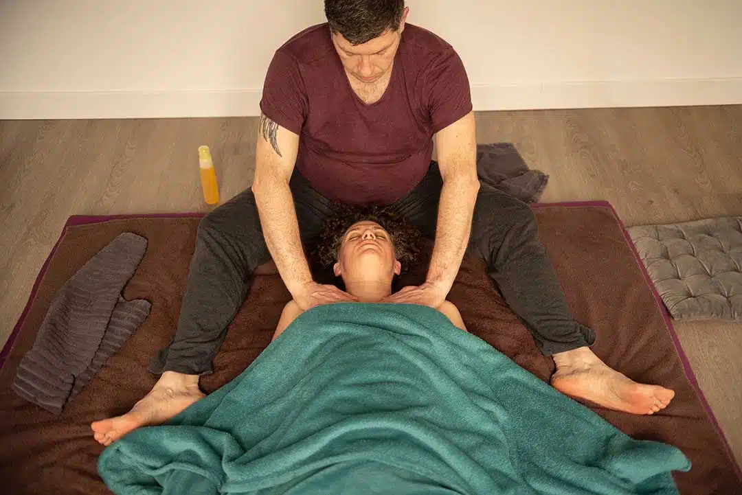 Moment de connexion entre le praticien en massage sur futon et la personne allongée sur le dos
