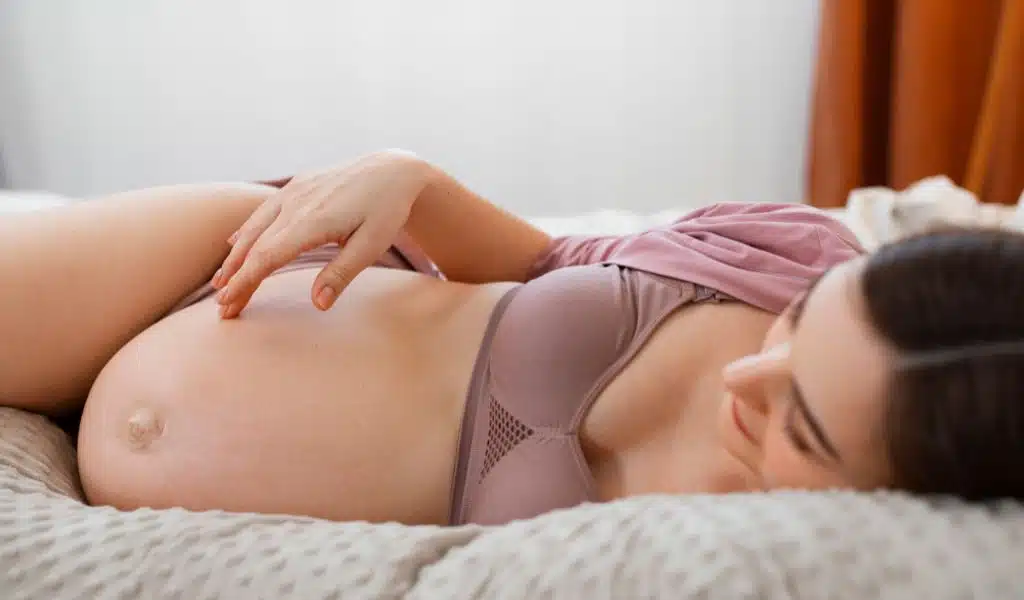 Femme enceinte en sous-vêtements, allongée sur le côté