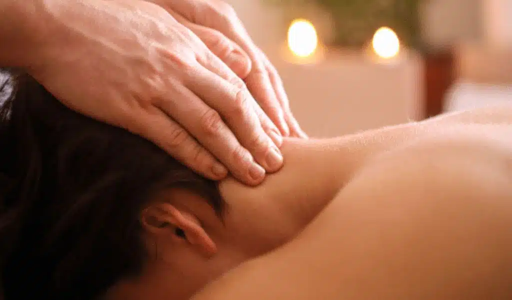 Mains massant la nuque et les épaules d'une personne allongée
