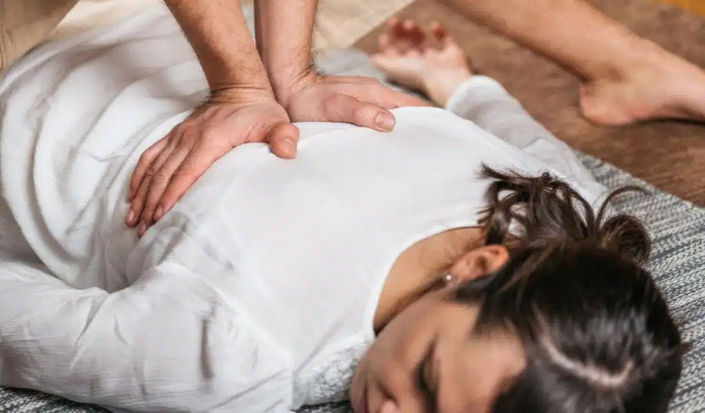 Mains posées sur le buste d'une femme allongée, les yeux fermés