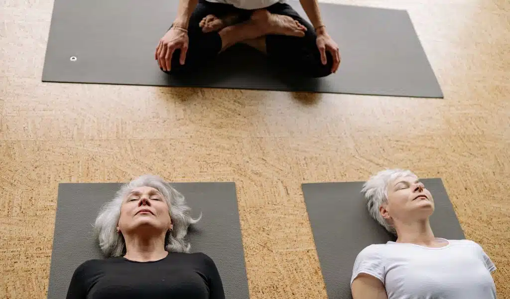 Deux femmes allongées sur des tapis, les yeux fermés, pendant un exercice de respiration