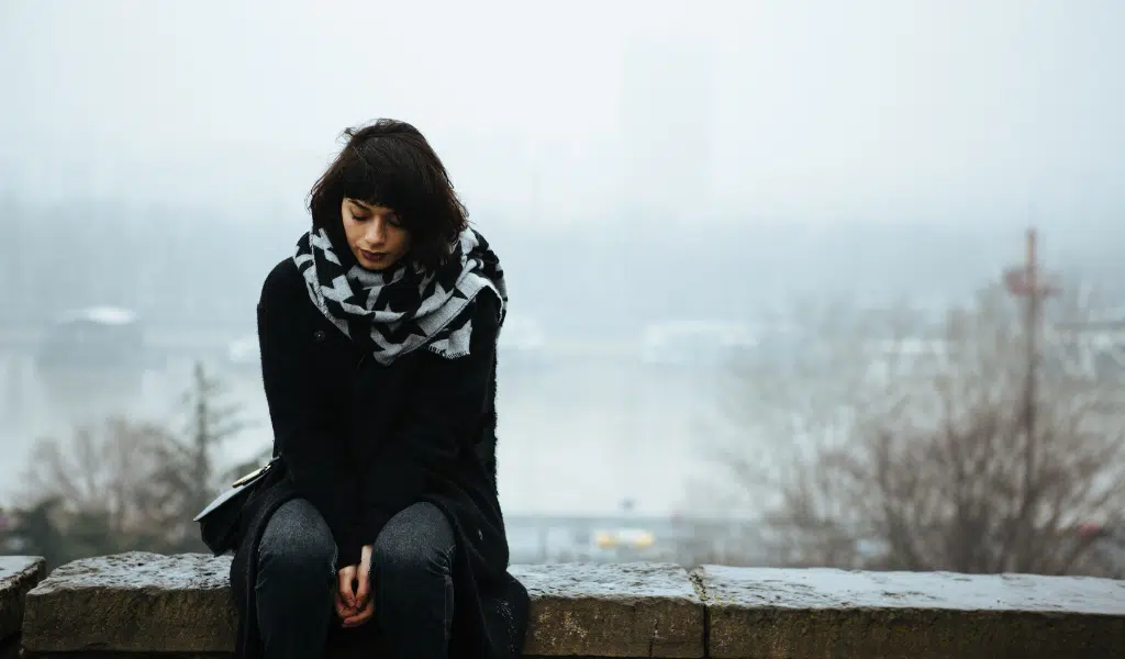 Femme assise seule dehors par temps gris, l'air triste