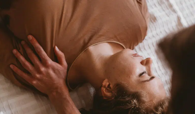 Main posée sur le haut du buste d'une femme allongée, les yeux fermés