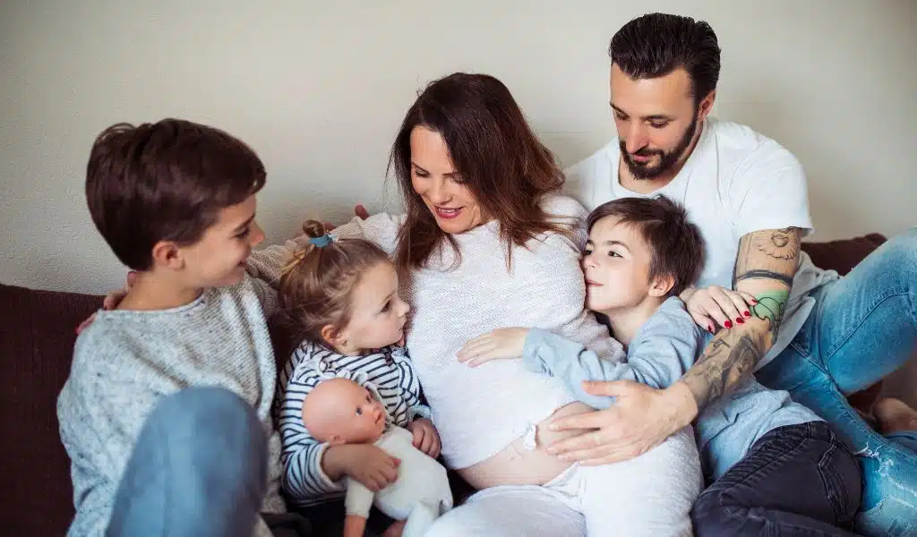 Famille réunie sur un canapé autour d'une femme enceinte